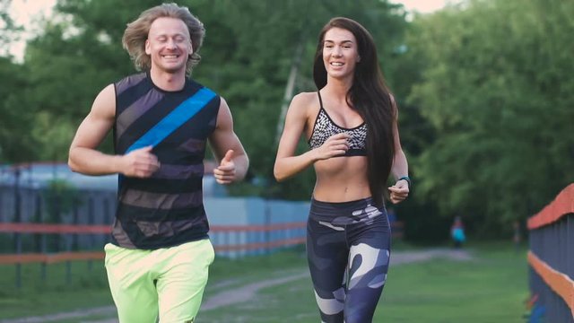 Man and woman commit a jog. They are young and attractive, communicate with each other positively.