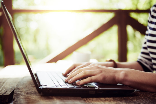 Close-up Of Female Hands Typing On Laptop Keyboard Outside. Young Businesswoman Working At Computer At The Desk.  