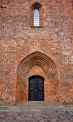 Entrance to Elsinore Cathedral with a black painted double wood door at the bottom of the tower built of red bricks