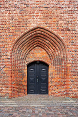The entrance door of black painted wood, in the church tower build from red bricks, of Elsinore Cathedral in Denmark