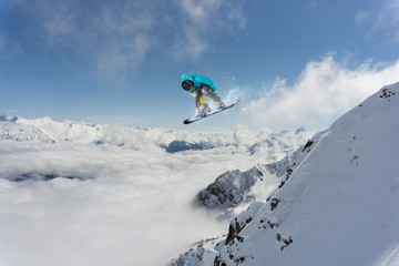 Naklejka na ściany i meble Snowboard rider jumping on mountains. Extreme snowboard freeride sport.