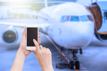 Hand holding mobile phone with blurred image of airplane backgro