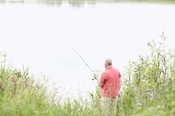 Mature angler catching fish on lake