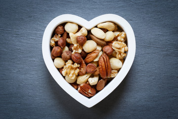 Heart shape bowl filled with mixed raw nuts