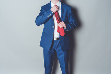 Portrait of successful businessman wearing blue siut and red tie against gray background