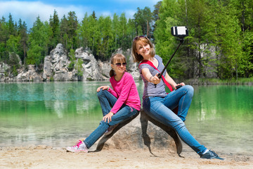 Fototapeta na wymiar Mother and daughter are doing Selfe on the shore of Piskovna lake. National Park of Adrspach-Teplice rocks. Rock Town. Czech Republic.