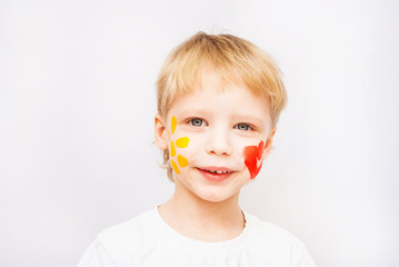 Beautiful smiling child face. Portrait of laughing emotional kid. Close up of cheerful funny boy isolated on white background. Baby with red heart and yellow sun on cheeks. Positive human emotions.