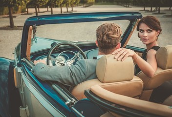 Wealthy couple in a classic convertible - obrazy, fototapety, plakaty