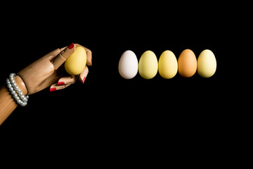 Woman's hand plays Newton's pendulum with eggs