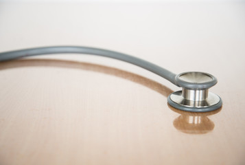 Close up view of grey stethoscope on brown background.