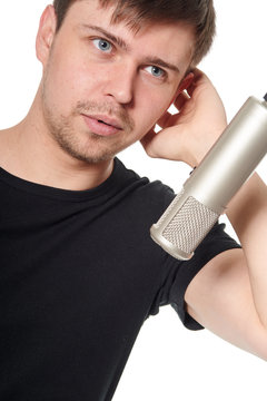 Close portrait of  handsome young man singing into studio microphone, on white