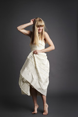 Naklejka premium Beautiful bride standing on tip toe in gray studio