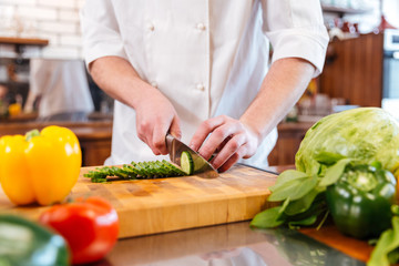 Hands of chef cook cutting vegetables and making salad