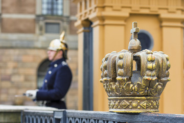 Swedish royal crown and soldier Royal Guard blurred in the background at the Royal Palace Square in...