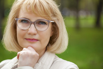 Close up portrait of lovely middle aged woman in the summer park