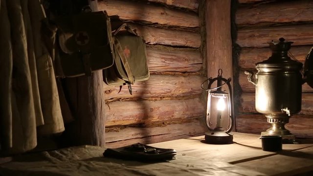 Ukrainian staff guerrilla dugout during the second world war. Military uniform, knapsack and first aid kit hangs on the wall. Oil lamp, samovar, topographic map and compass lies on the table