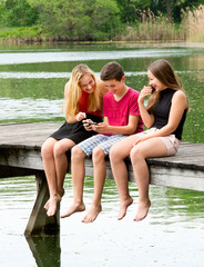 Fototapeta premium Drei Teenager haben draußen Spaß mit Smartphone