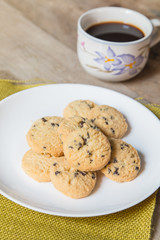 Chocolate chips cookies served with coffee on a wooden table.