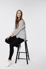 Confident woman sitting on stool, portrait