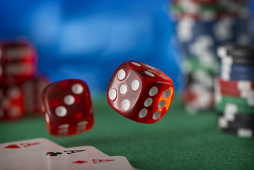 Two red dice rotates in the air, casino chips, cards on green felt