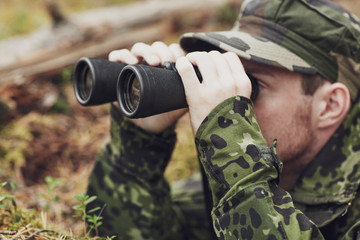young soldier or hunter with binocular in forest