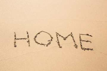 Fototapeta na wymiar word home written in sand on beach