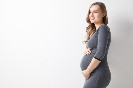Fototapeta Isolated portrait of beautiful smiling woman in dress waiting for baby