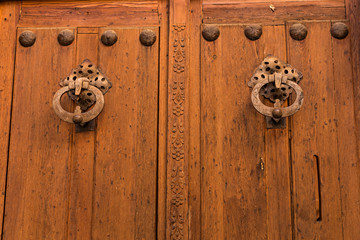 Puerta de madera con llamadores metálicos.