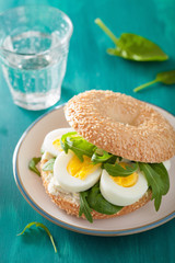 breakfast sandwich on bagel with egg cream cheese arugula