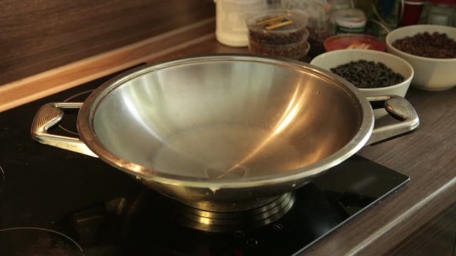 Pouring oil into frying pan. Man pours oil on the hot pan on electromagnetic plate