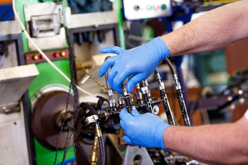 Professional mechanic testing diesel injector in his workshop.