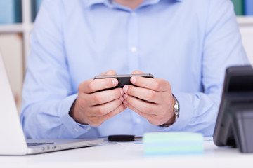 Geschäftsmann im Büro tippt SMS in Smartphone © TeamDF