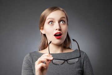 Amazed woman holding glasses while looking up