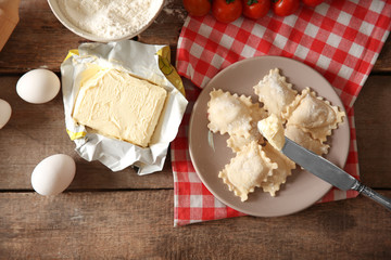 Uncooked ravioli on plate on wooden table