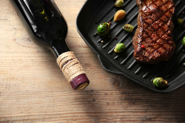 Obraz premium Grilled steak on grill pan with wine on wooden table