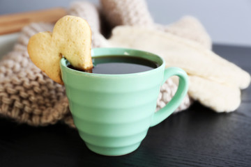 Heart shape cookie on cup of coffee on wooden table closeup