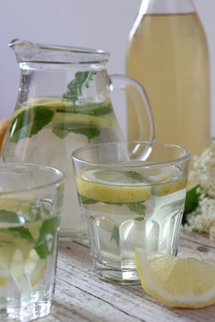 Bicchieri e caraffa con bibita di acqua limone e menta