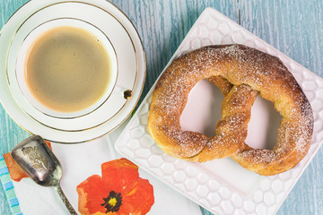 Fresh baked soft cinnamon flavored pretzel and cup of coffee.