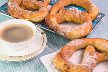 Fresh baked soft cinnamon flavored pretzels and cup of coffee.