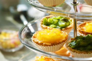 Fresh homemade fruit tarts with citruses and kiwi on a white table.