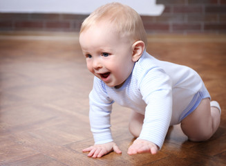 Crawling baby on the wooden floor in the room
