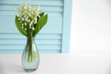 Bouquet of lilies of the valley in vase on light background