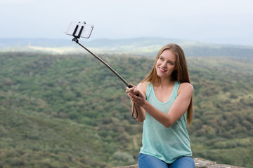Junge hübsche Frau macht ein Selfie mit einem Selfie Stick während der Ferien und hat Spaß dabei