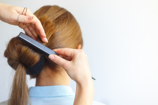 Professional female hairdresser making hairstyle to cheerful young woman with long hair