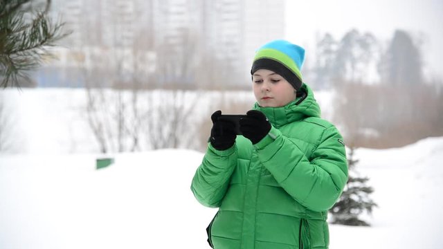 boy uses a cell phone with gloves outside in winter