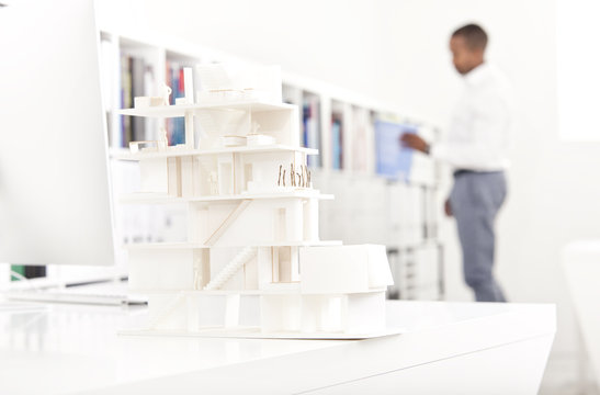 Architectural model on desk in an office with man in the background