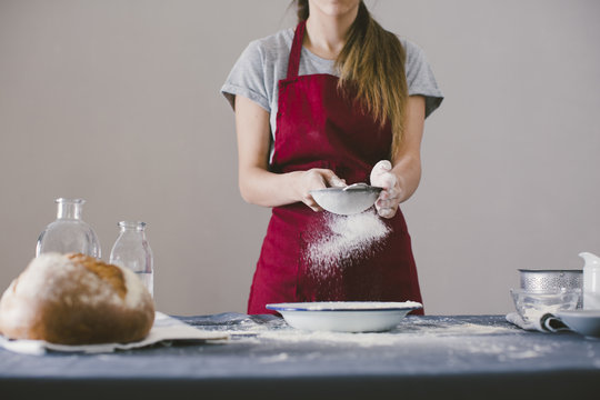 Woman preparing home made bread, sieving the flour