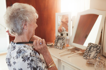 Senior woman combing her hair at dresser in house