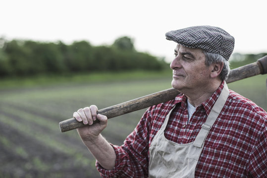 Farmer holding tool in front of a field