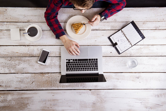 Man working at laptop while having coffee and cake